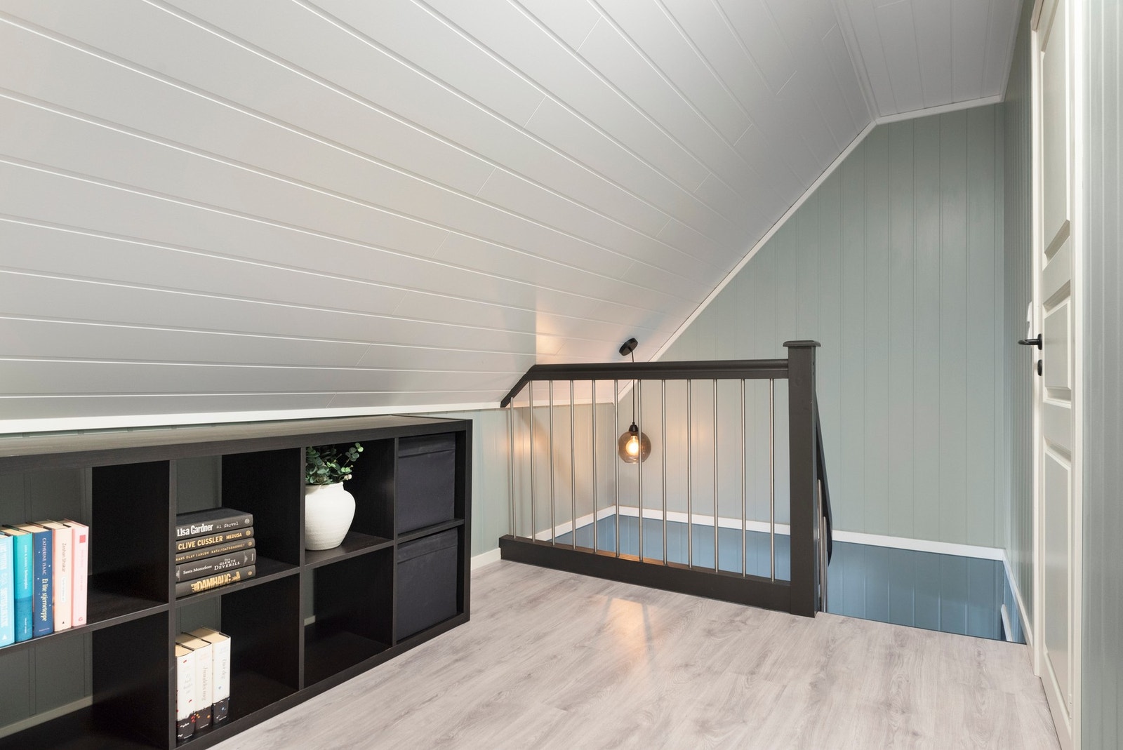 Lyst loftsrom med skråtak, rekkverk og innebygd hylle. Galleribilde