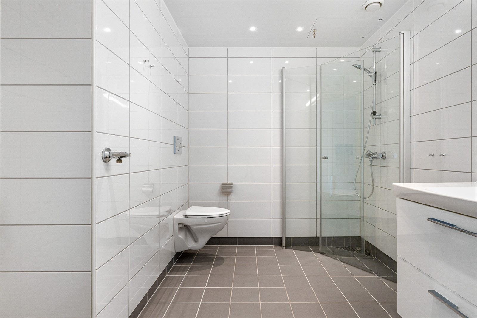 Badet har en moderne og plettfri standard, hvor takstmann har gitt TG1 på alle punkter. Her får du vegghengt toalett som er montert høyere, dusjhjørne med innfellbare glassdører, servant med underskap for enkel oppbevaring og belysning over speil. Galleribilde