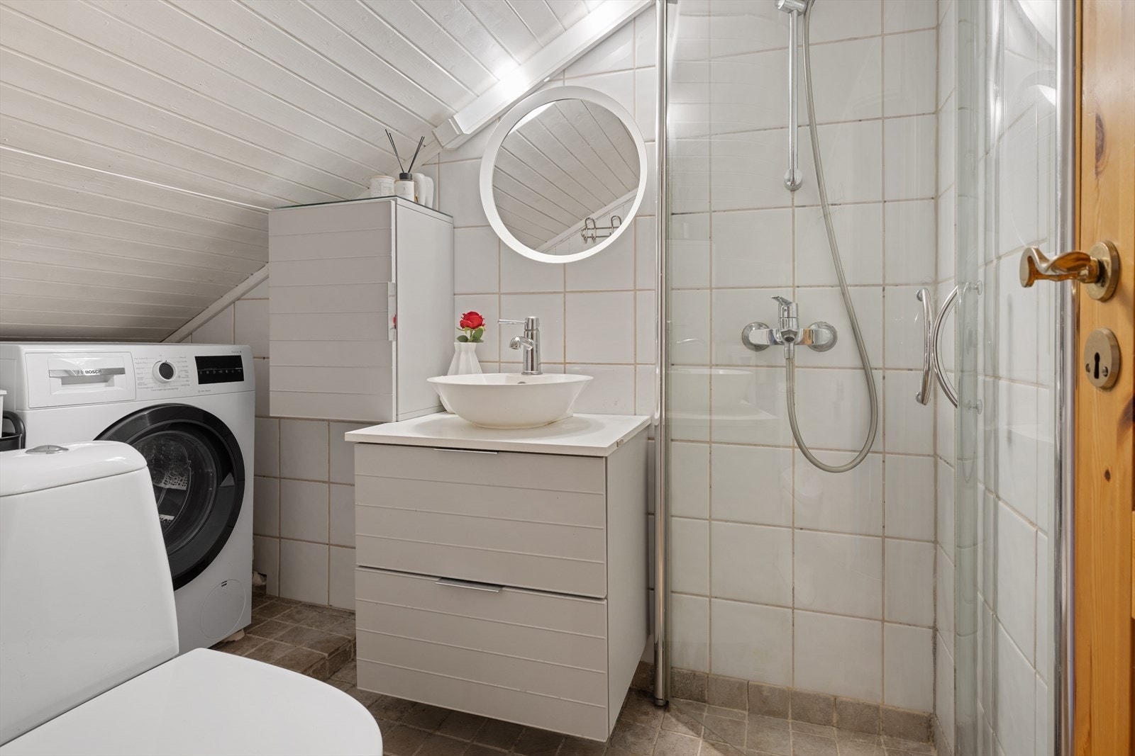 Baderommet har dusjløsning, servant på skuffeseksjon og gulvstående toalett. Galleribilde