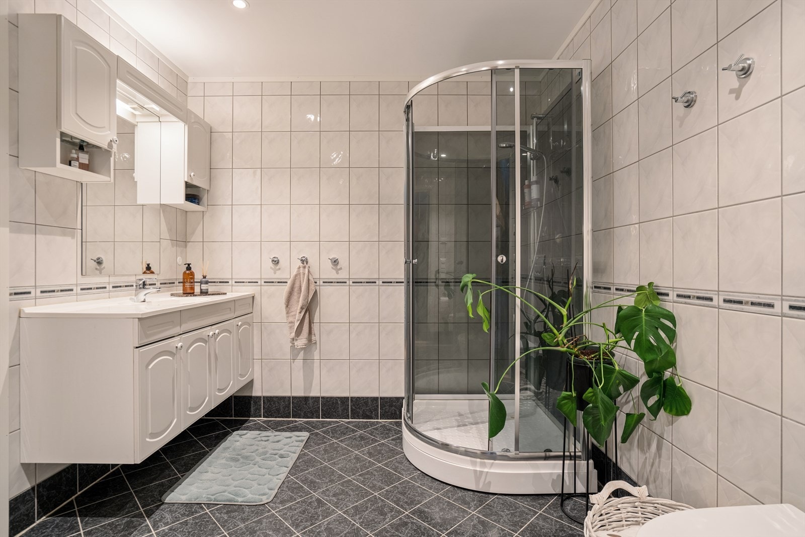 Rommet er innredet med baderomsinnredning med nedfelt servant, vegghengt toalett og et dusjkabinett som utnytter plassen godt. Galleribilde