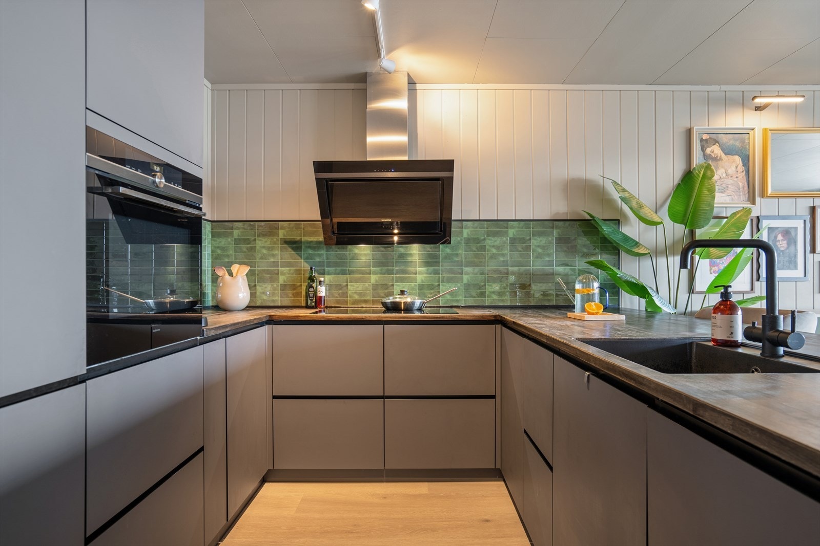 Kjøkkenet fra 2006 har en moderne og tiltalende innredning med glatte fronter og benkeplate i heltre som gir et varmt og stilrent preg. Galleribilde