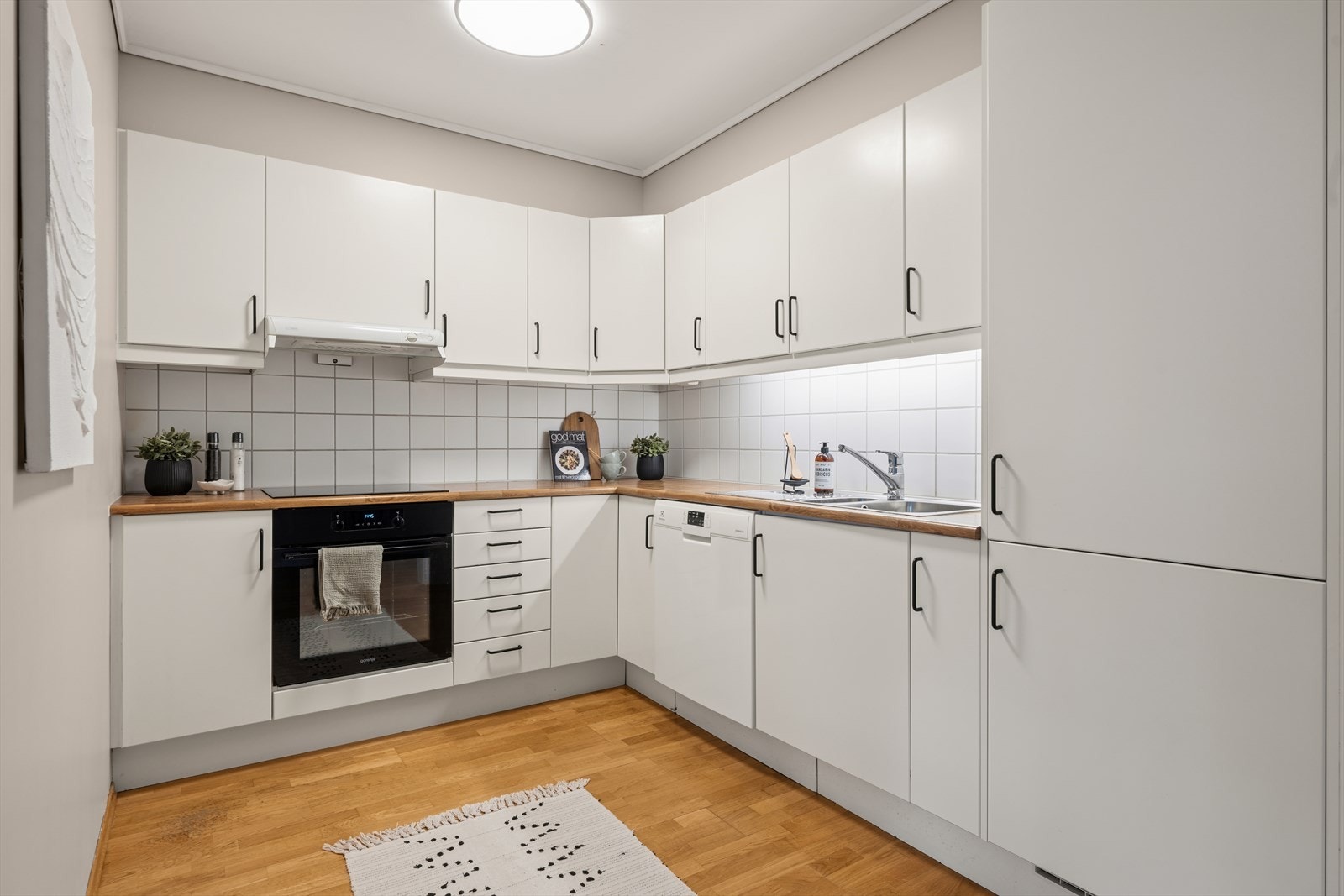 Kjøkkenet har en praktisk løsning som gir godt med skap- og benkeplass. Galleribilde