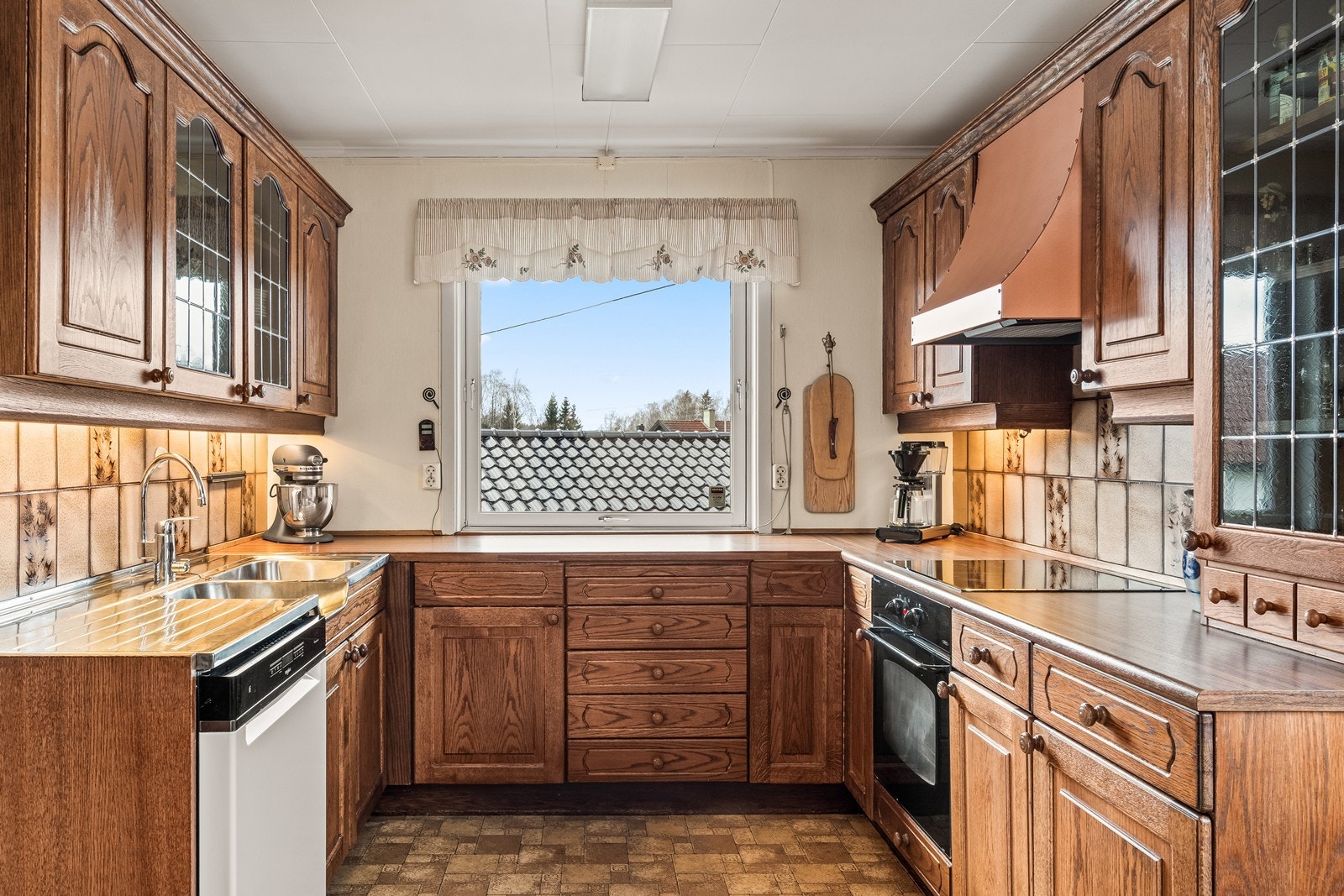 Kjøkkeninnredningen har profilerte fronter i tre og laminerte benkeplater. Galleribilde