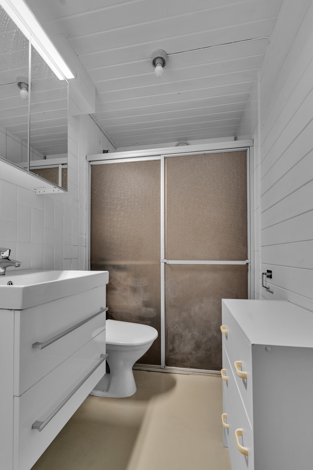 Badet i underetasjen har eldre standard og må oppgraderes for å tåle normal bruk i henhold til dagens krav. Gulvet er malt mur, og badet har eldre dusjgarnityr og toalett, og nyere innredning. Galleribilde