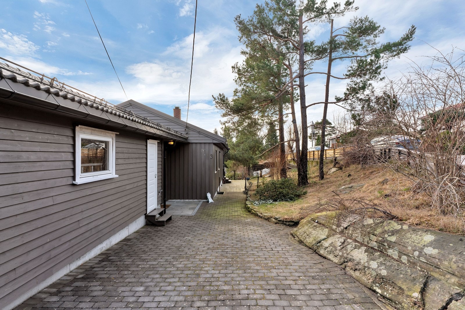 Boligen har en asfaltert gårdsplass som også er delvis opparbeidet med belegningsstein, noe som gir et pent og ryddig førsteinntrykk. Galleribilde