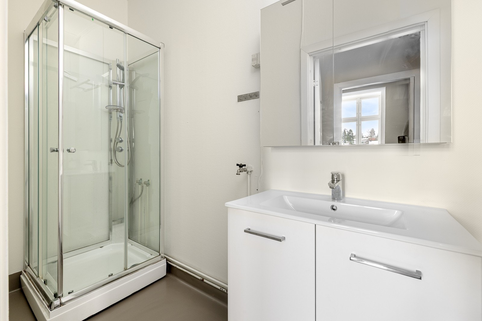 Badet er originalt fra 1989, og oppussing må påregnes. Rommet har en oppgradert innredning med nedfelt servant fra 2025, dusjkabinett og opplegg for vaskemaskin. Galleribilde