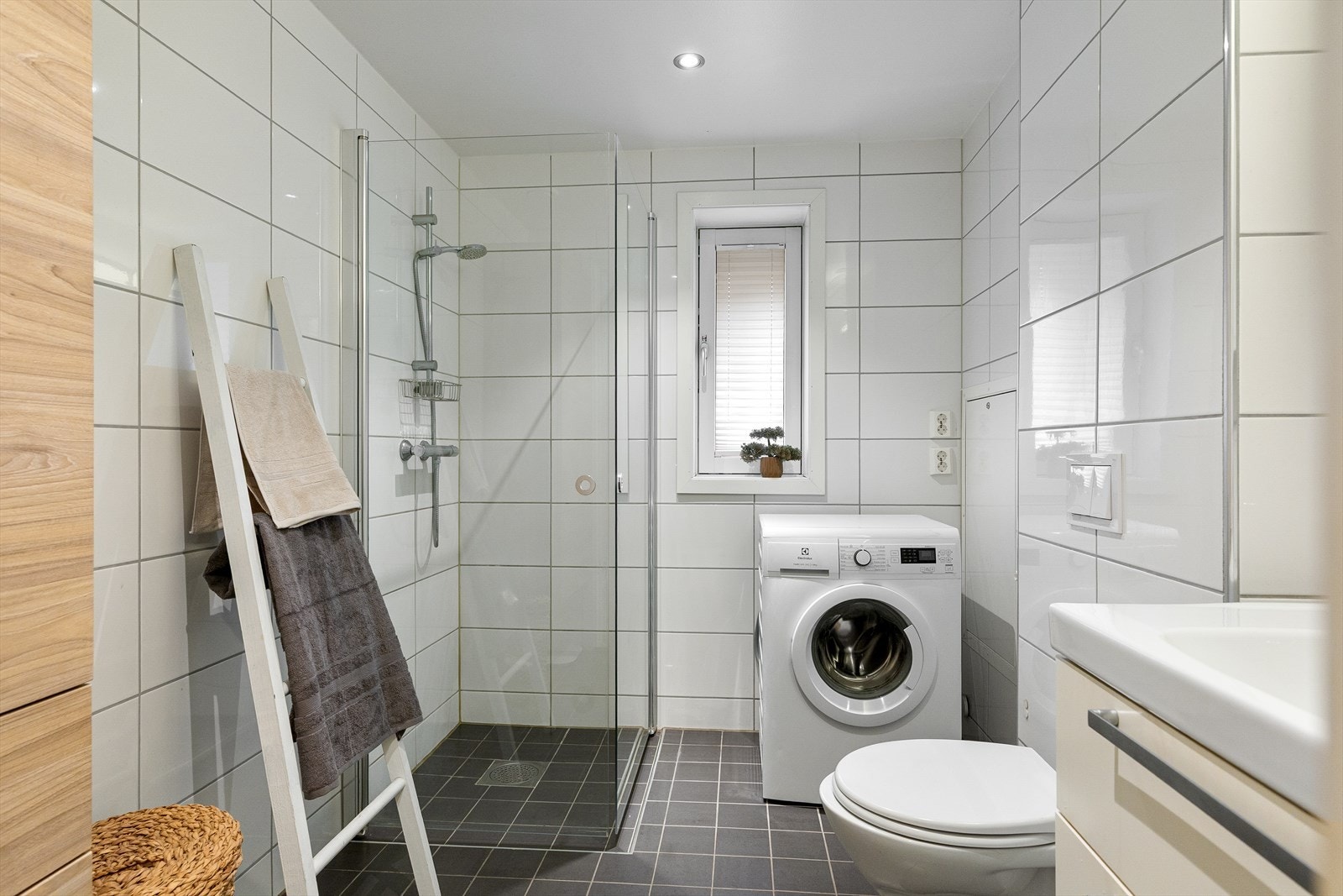 Badet er utstyrt med veggmontert WC, dusjplass med inn- og utadslående dusjvegger, samt servant med ettgreps blandebatteri i praktisk innredning. Galleribilde