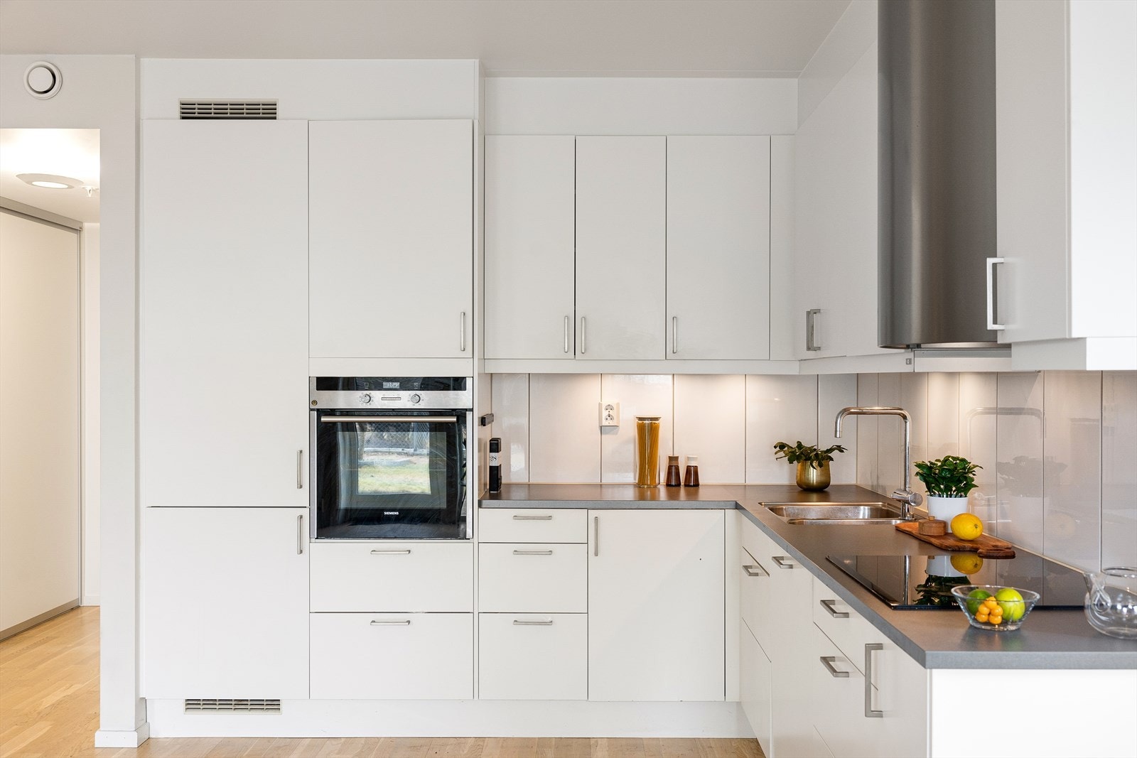 Kjøkkenet har en stilren, glatt laminert innredning med fliser mellom over- og underskap, samt laminert benkeplate med nedfelt kum og ettgreps blandebatteri. Galleribilde