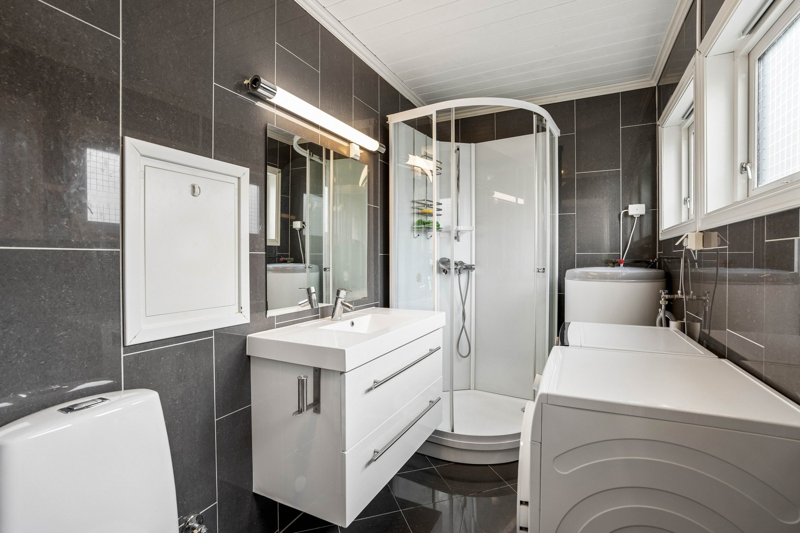 Bad med baderomsinnredning med nedfelt servant, dusjkabinett og toalett. Galleribilde