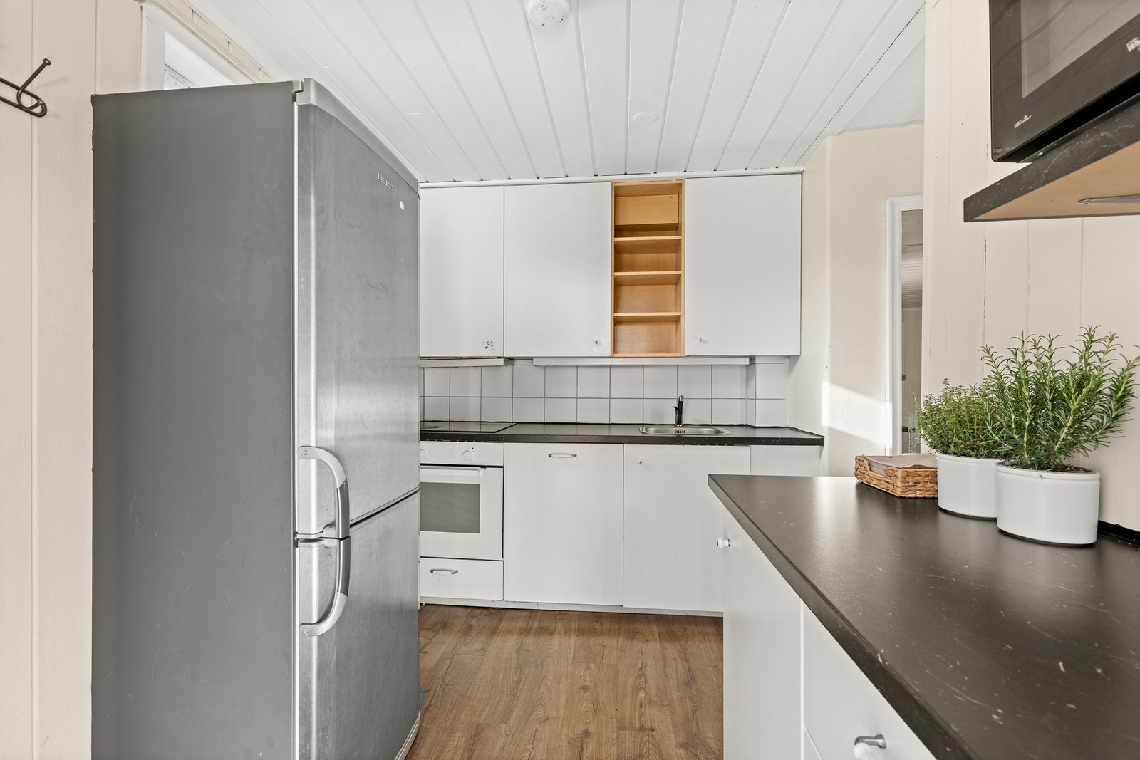 Kjøkkenet har en innholdsrik innredning med hvite glatte fronter og benkeplater av laminat. Galleribilde