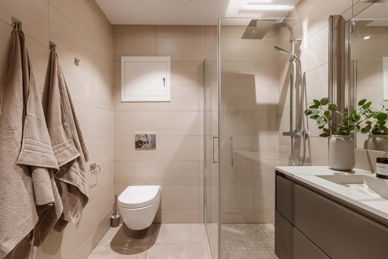 Leiligheten har et flislagt bad ved entréen, oppført i byggeåret. Badet har en praktisk og moderne innredning med servantskap med glatte, fabrikklakkerte fronter og heldekkende servant. Galleribilde