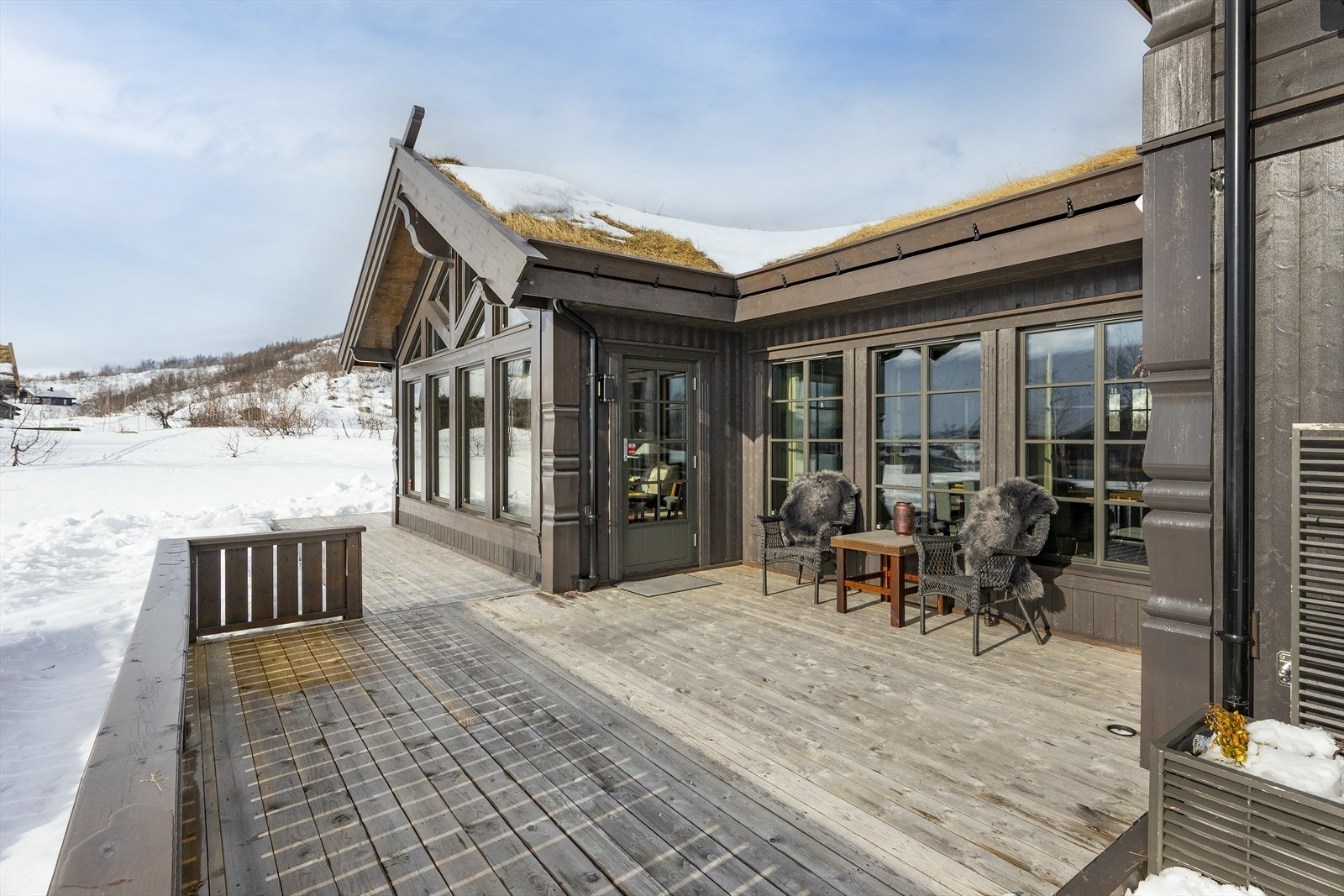 Terrassen på forsiden av hytta er bygget med impregnerte materialer og har rekkverk med stående bord. Galleribilde