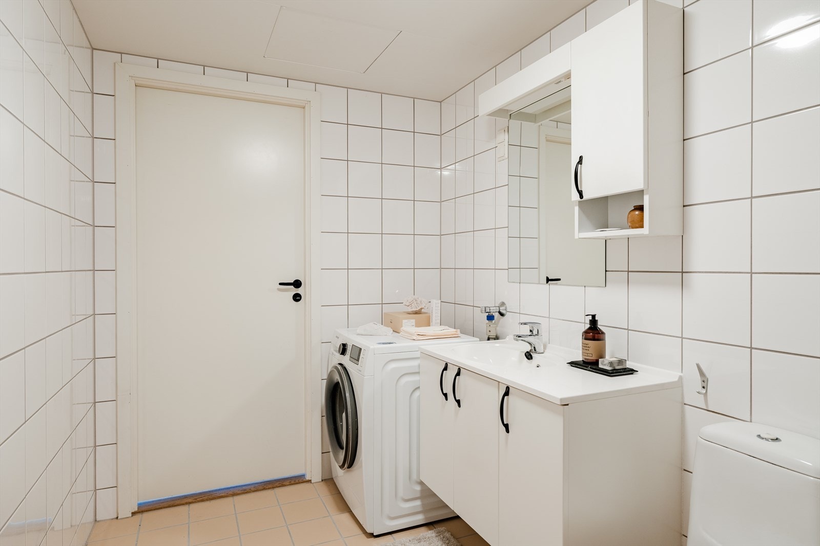 Badet er innredet med toalett og dusjhjørne med dusjdører i glass. Baderomsinnredning med veggskap og speil gir gode oppbevaringsmuligheter Galleribilde