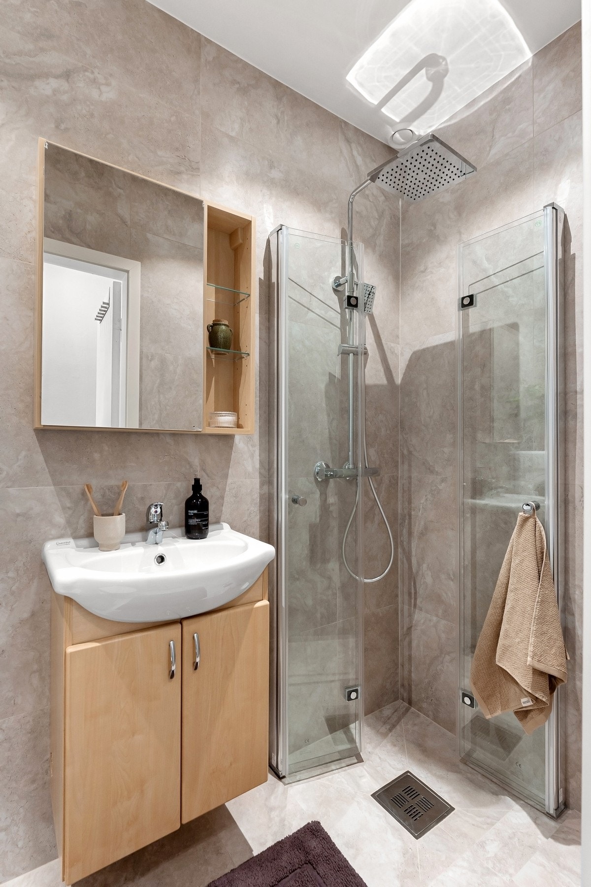 Delikat flislagt baderom i lys utførelse, totalrenovert i 2025. Badet er utstyrt med nedsenket dusjhjørne med svingdører i glass og regnfallsdusj Galleribilde