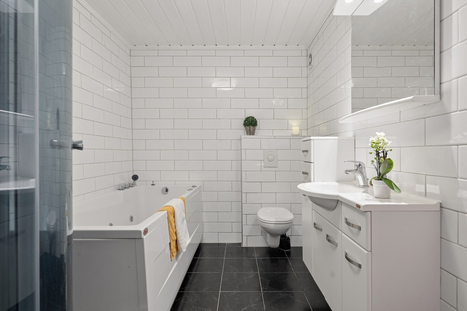 Lekkert renovert baderom i underetasjen med både boblebadekar, dusj, rikelig med innredning samt vegghengt klosett Galleribilde