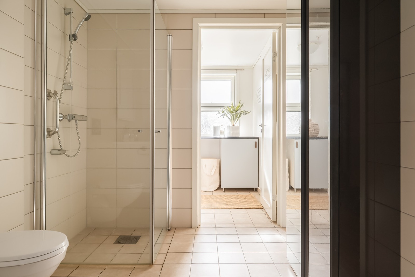 På badet er det vegghengt toalett, servant med innredning, dusjvegger av glass og dusjgarnityr på vegg. Galleribilde