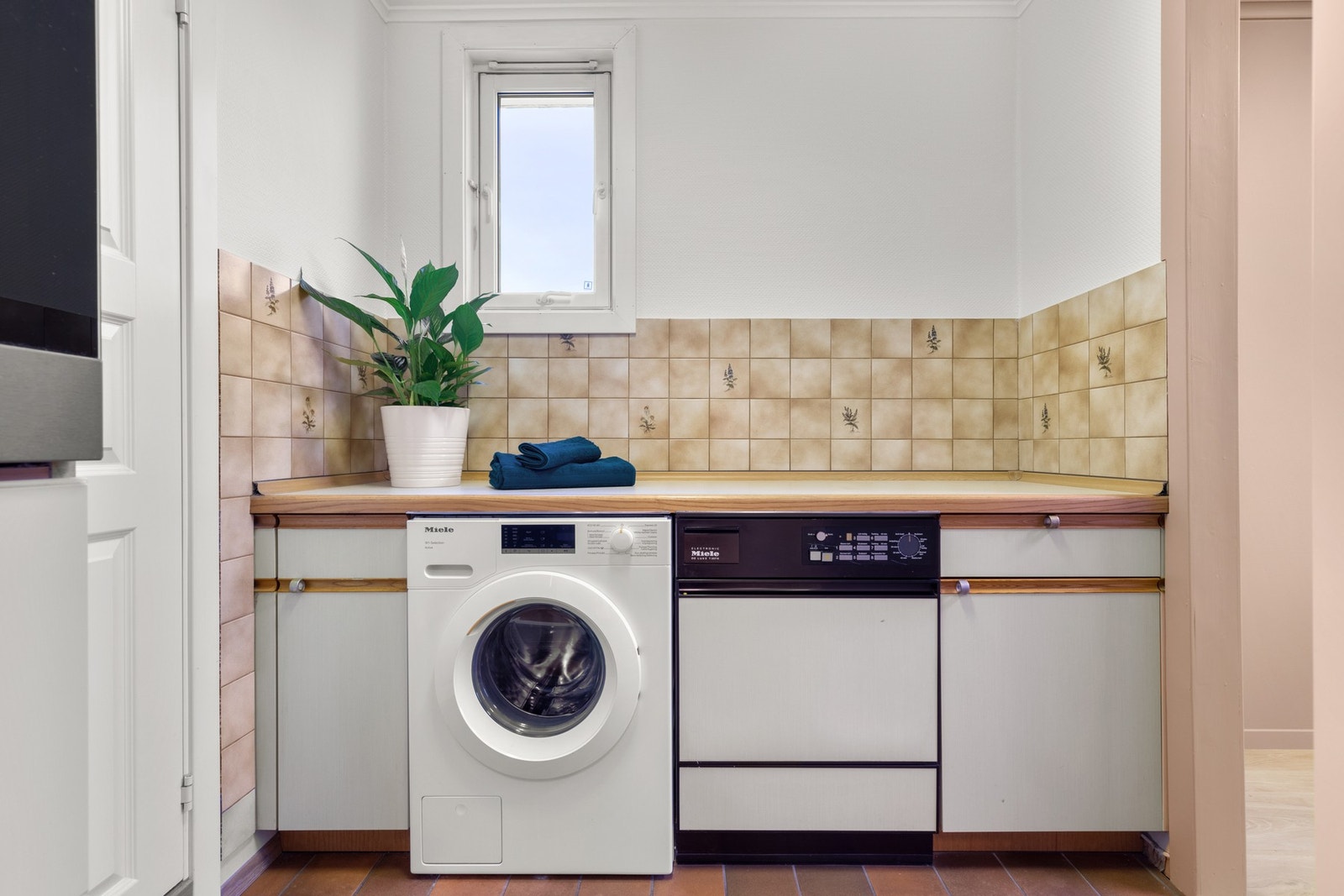 I enden av kjøkkenet finners en innredning med en integrert vaskemaskin for klær og en praktisk benk Galleribilde