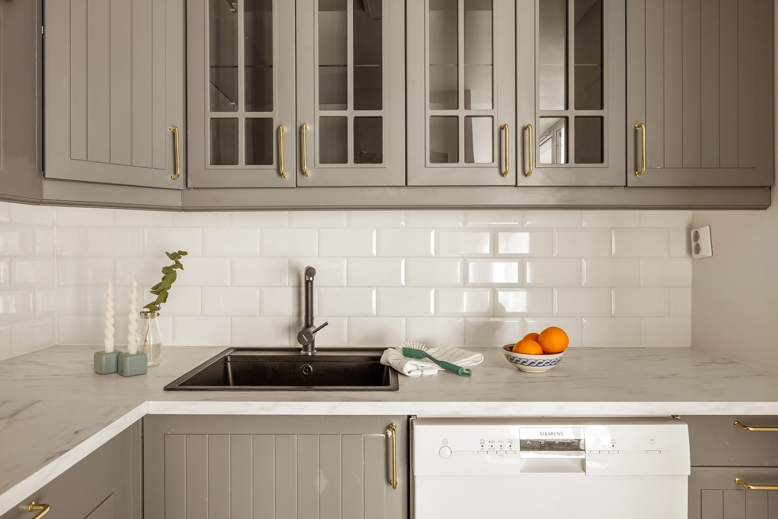 Innredningen har profilerte fronter, laminatbenkeplate og fliser over benken. Overskap med glassfronter gir et luftig preg. Galleribilde