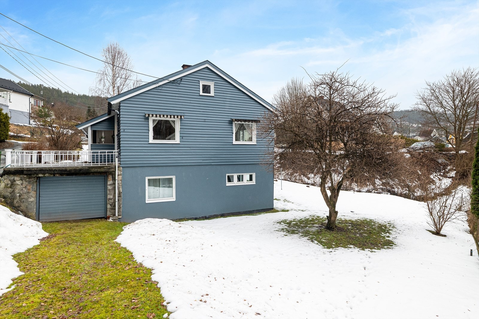 Boligen er tilbygget med en enkel garasje i underetasjen. Over garasjen er det anlagt en støpt platting ved inngangspartiet. Galleribilde