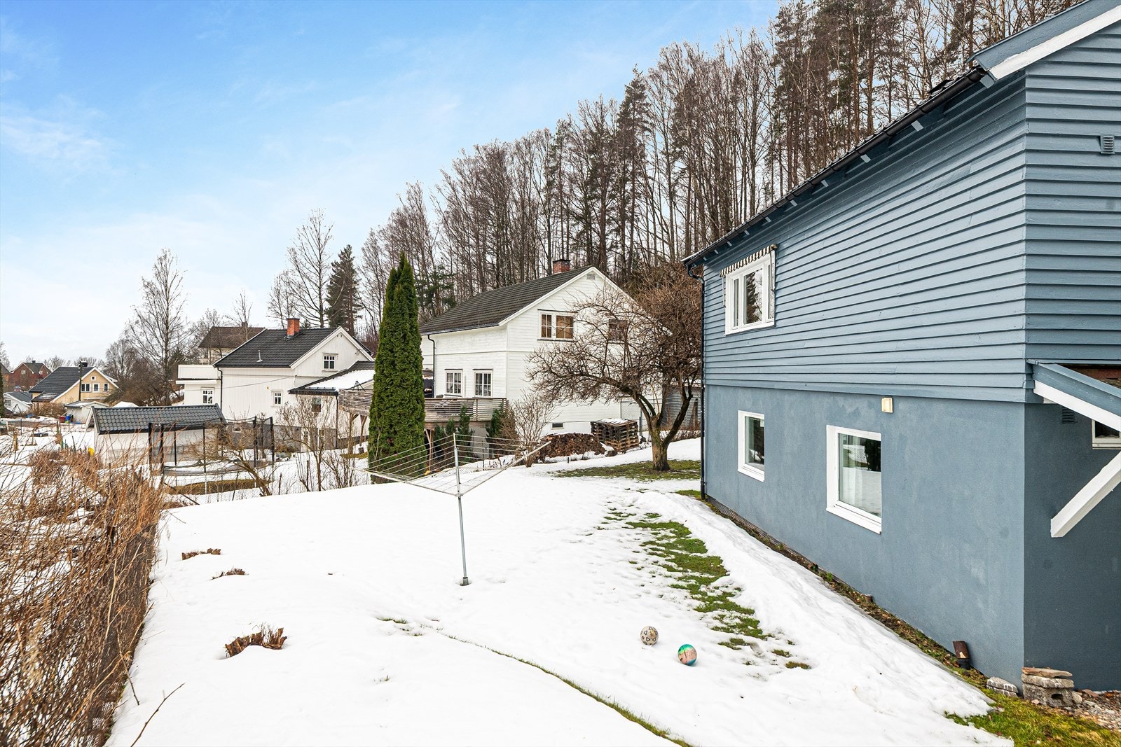 Romslig tomt i skrånende terreng, pent opparbeidet med plen og diverse beplantning, samt noe asfalt langs vei. Galleribilde
