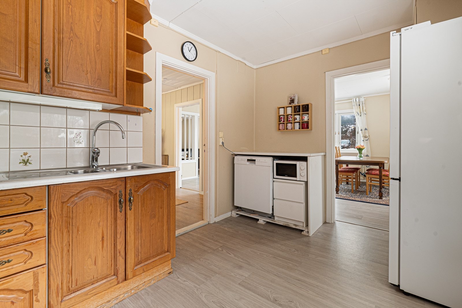 Flis på vegg over laminat benkeplate med gode arbeidsflater og nedfelt benkebeslag. Avsatt plass til frittstående hvitevarer. Galleribilde