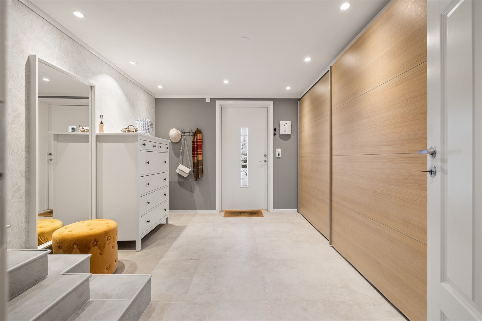 Velkommen inn! Lys og åpen entré som gir et godt førsteinntrykk av huset. Det er fliser på gulv og skyvedørsgarderobe som dekker hele veggen Galleribilde