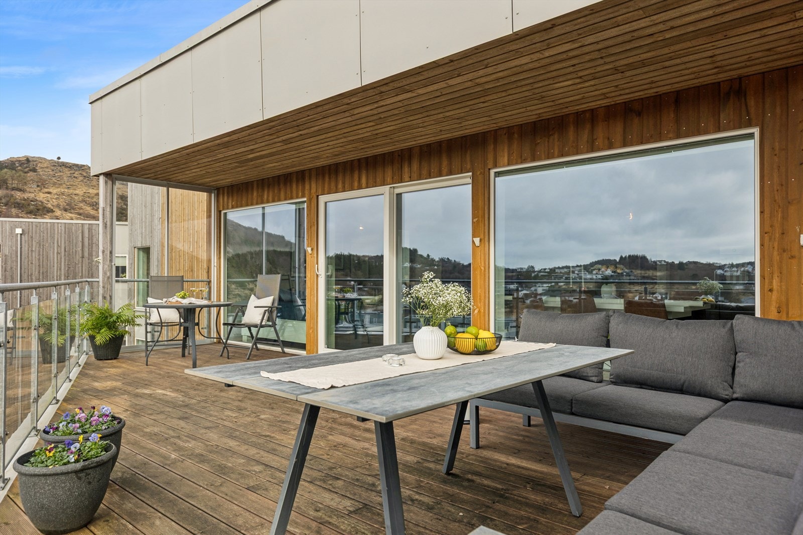 Innbydende uteplass med god plass til både spisegruppe og loungemøbler, rammet inn av moderne materialer og en flott utsikt. Galleribilde