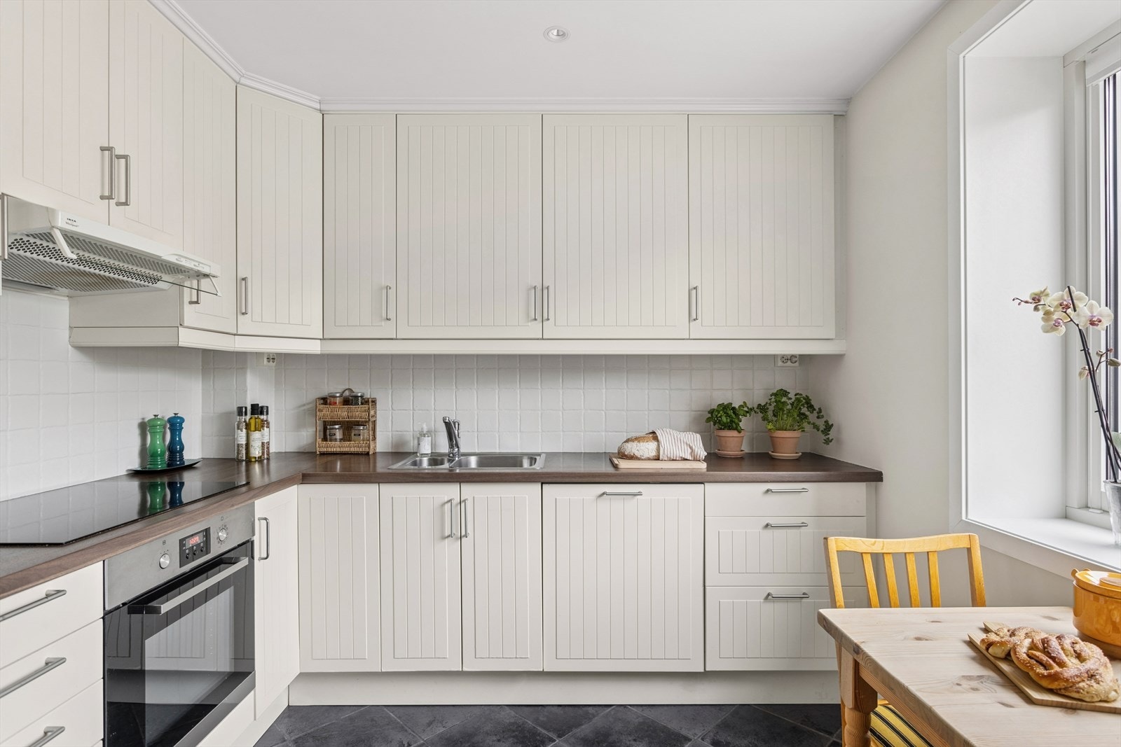 Kjøkkeninnredningen har lakkerte/malte profilerte formpressede fronter med laminat benkeplate Galleribilde