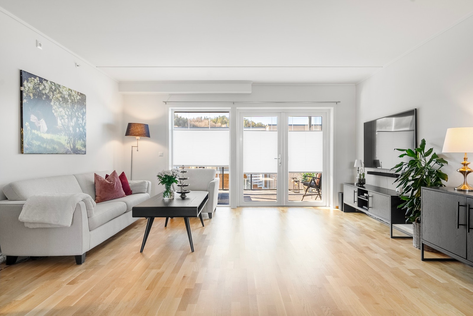 Åpen stue med god plass til romslig sofa og store vindusflater som slipper inn rikelig med lys og åpner rommet mot balkongen Galleribilde