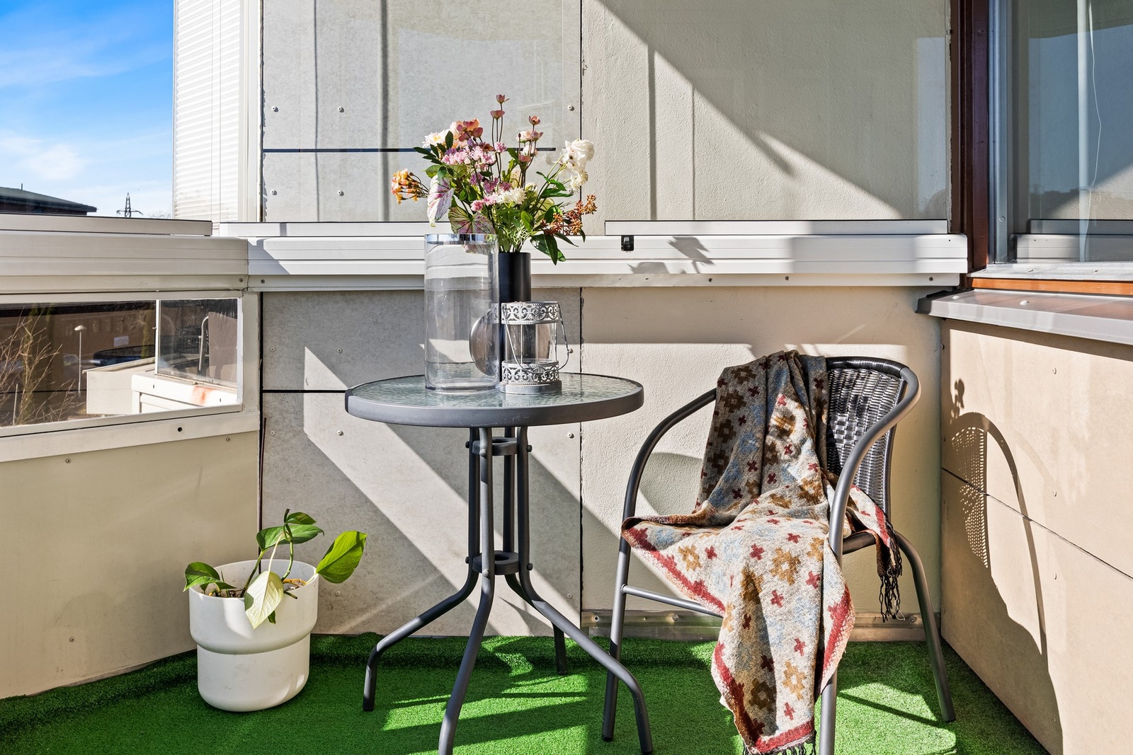 Detaljbilde av balkongen med sittegruppe som gir en lun og innbydende atmosfære for kaffe i solen. Galleribilde