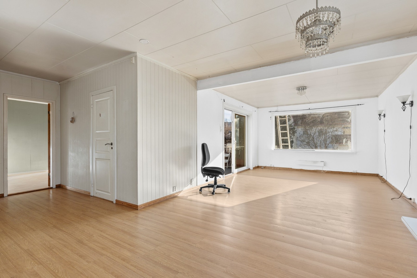 Stue med laminatgulv, veggflater med slette flater og panelplater samt takplater i himling Galleribilde