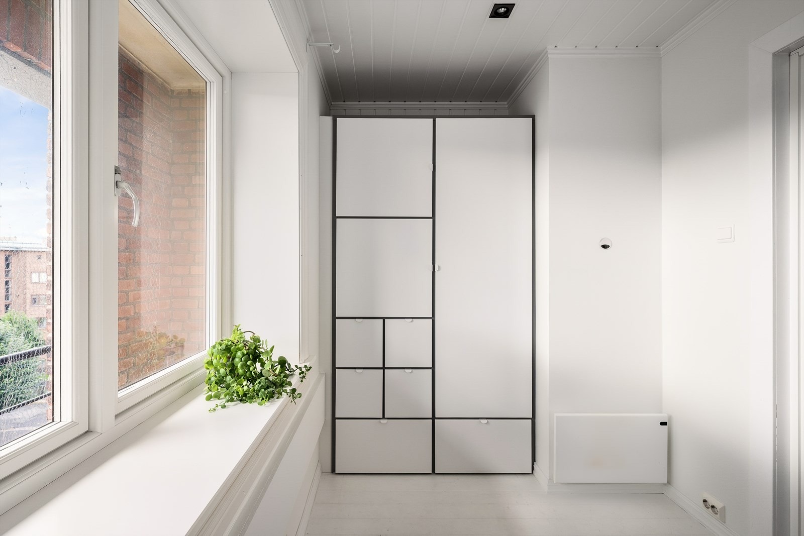 Rommet har praktisk oppbevaring i et integrert garderobeskap med hvite folierte fronter. Galleribilde