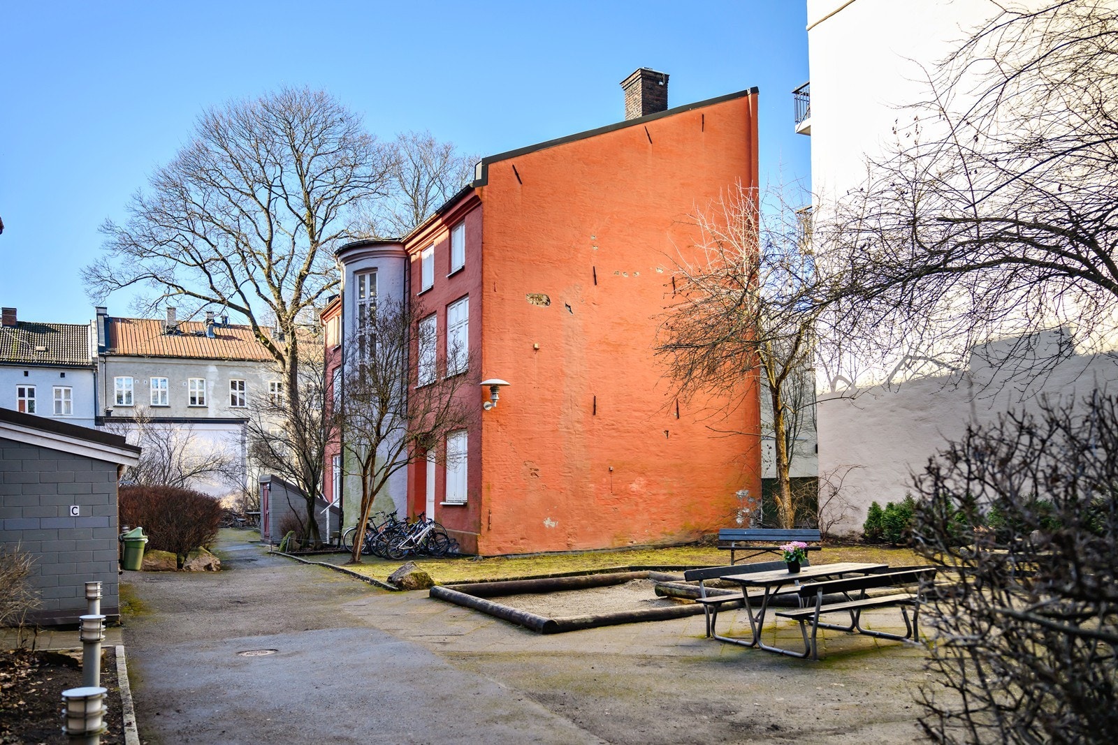 Bakgården har bl.a. hellelagt uteplass med sandbasseng og et antall felles sittegrupper. Galleribilde