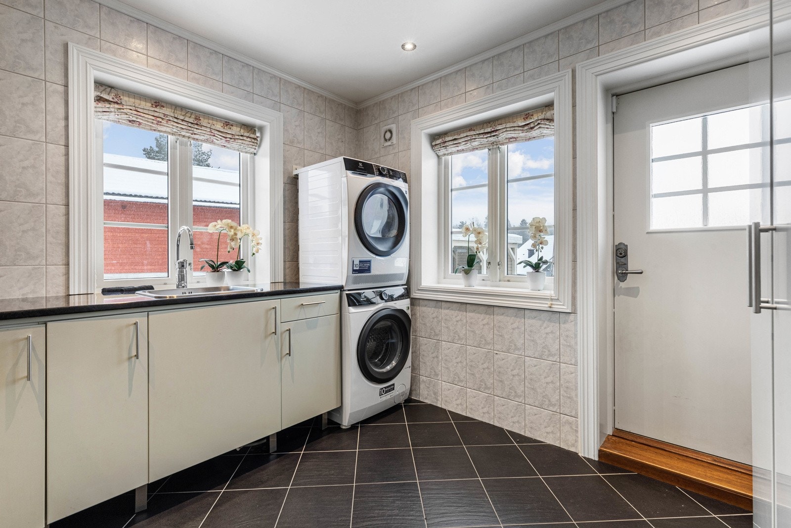 Vaskerommet er innredet med benkeplate med vask, samt overskap og underskap. Nisje med opplegg for vaskemaskin og tørketrommel. Galleribilde