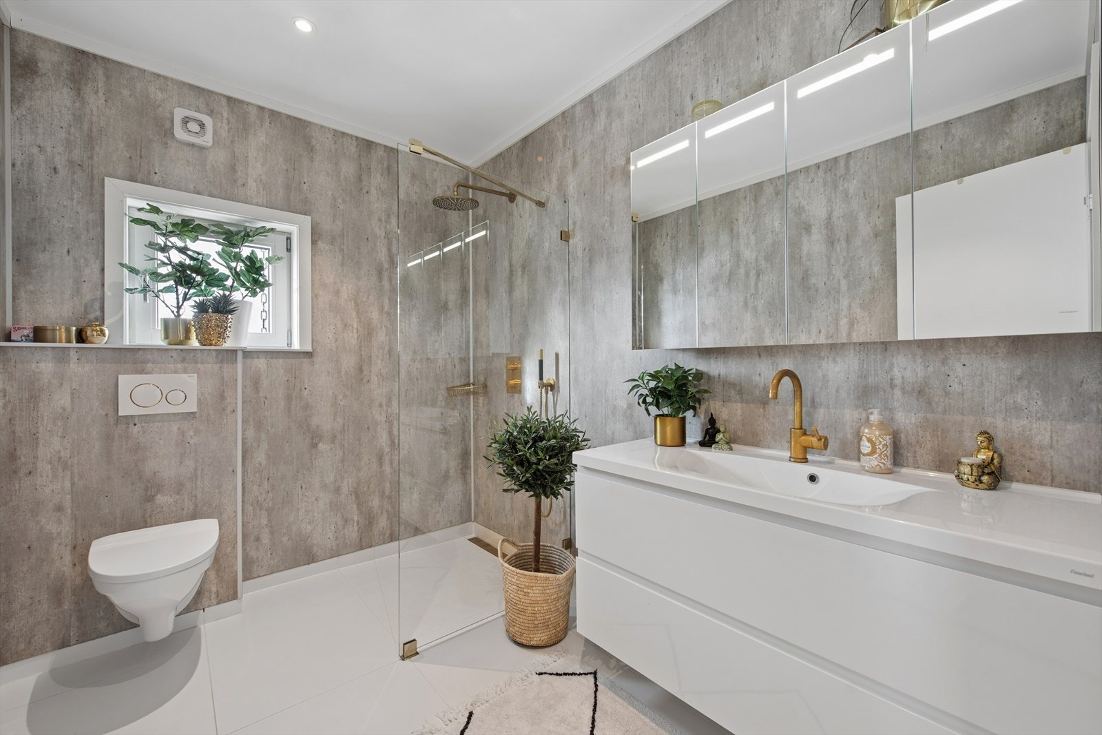 Badet i 1. etasje har et stilrent uttrykk med hvitt flislagt gulv med elektriske varmekabler og grå baderomsplater på veggene Galleribilde
