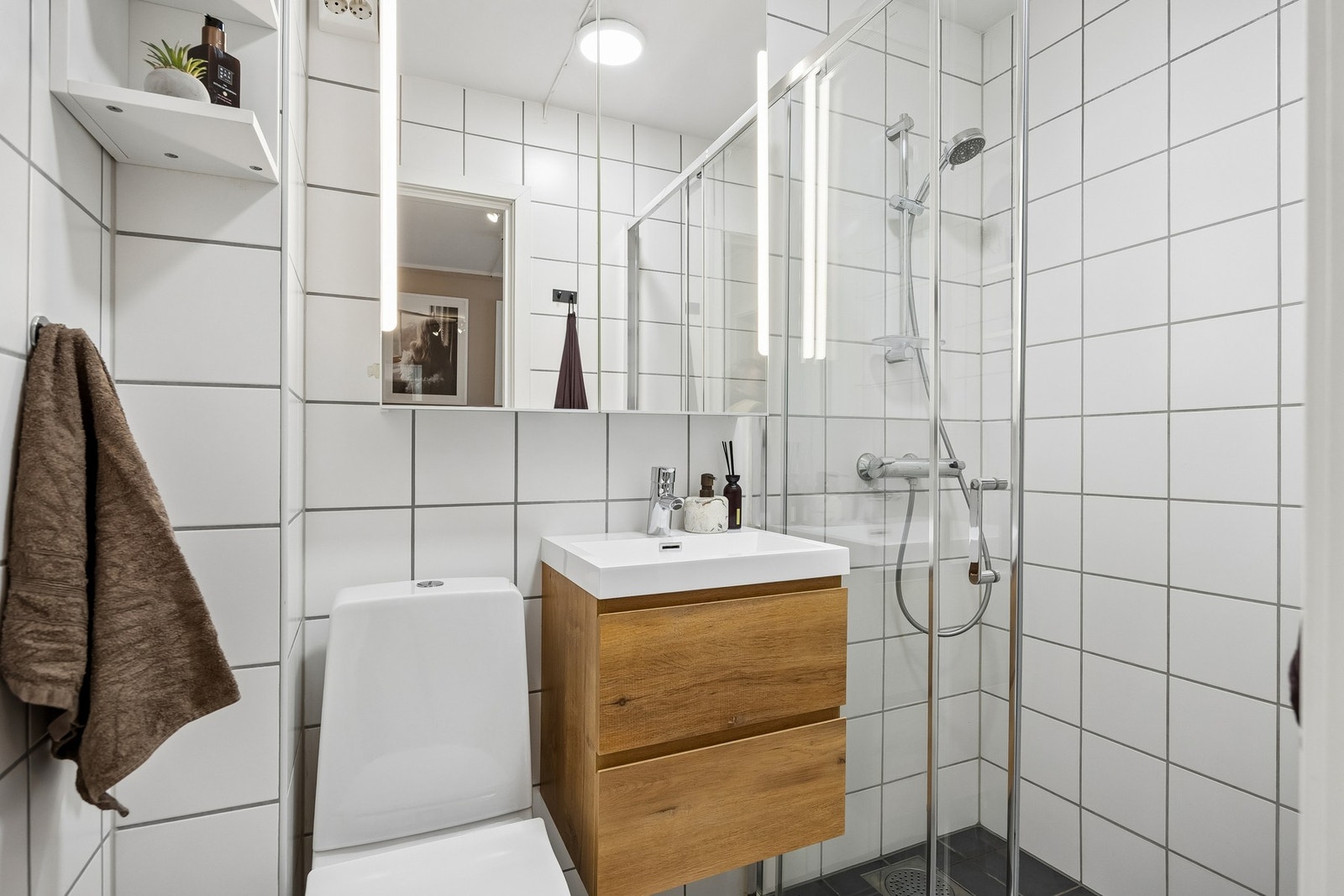 Badet er praktisk utformet med flislagte overflater på gulv og vegger, noe som gir et tidløst og lettstelt uttrykk. Galleribilde