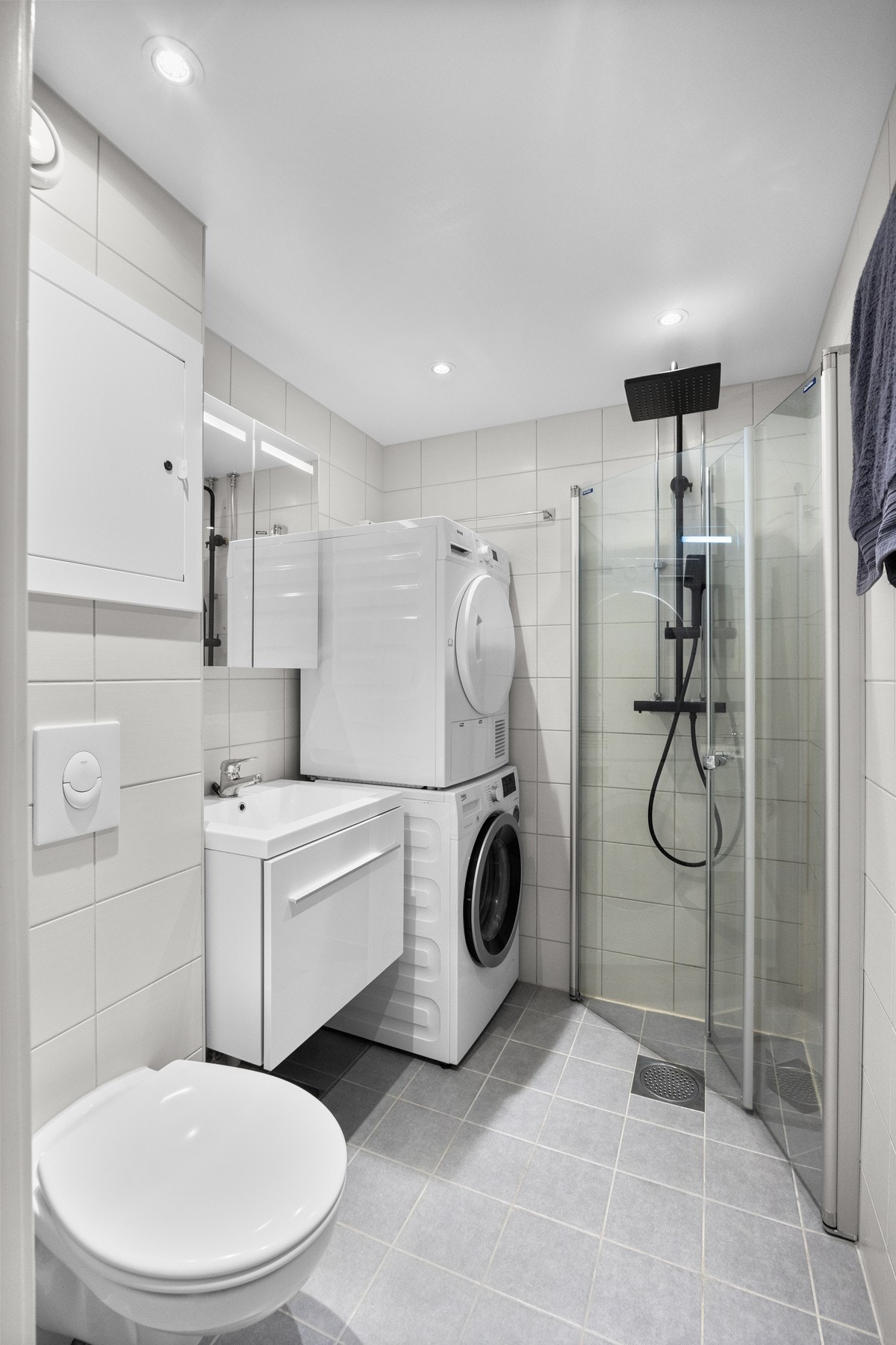 Bad/vaskerom med veggmontert toalett, opplegg for vaskemaskin, speilskap med integrert
belysning, baderomsinnredning med høyglans front og heldekkende servant. Galleribilde