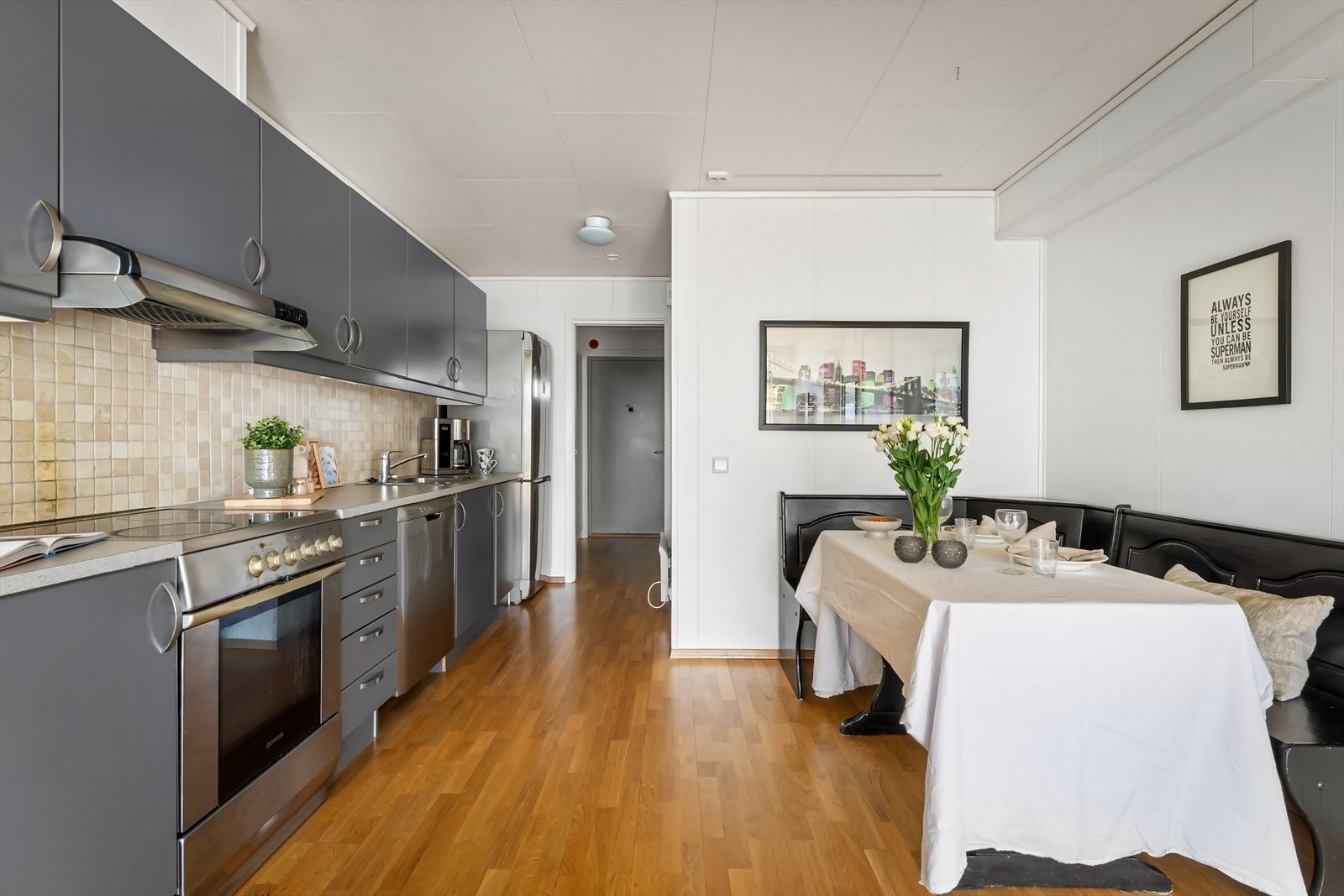 Pent og funksjonelt kjøkken med moderne, glatte fronter og flislagt backsplash som gir et stilrent og lettstelt uttrykk. Galleribilde