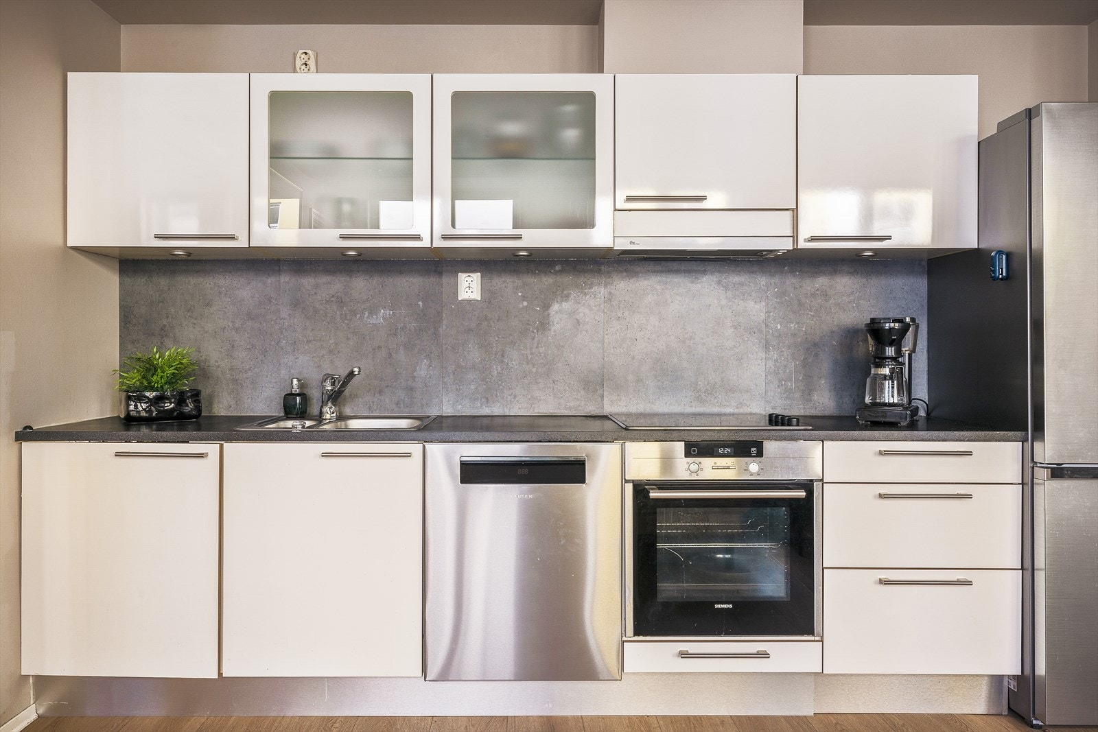 Kjøkkenet inneholder laminert benkeplate, stål vaskekum, ventilator og opplegg for oppvaskmaskin Galleribilde