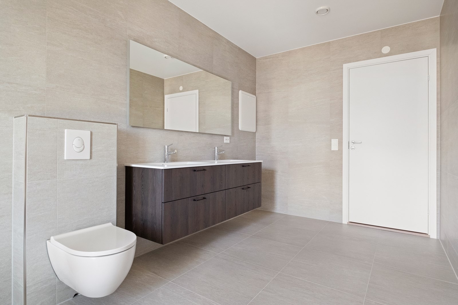 Det er utstyrt med dusjdører, vegghengt WC og en innredning med 2 servanter Galleribilde