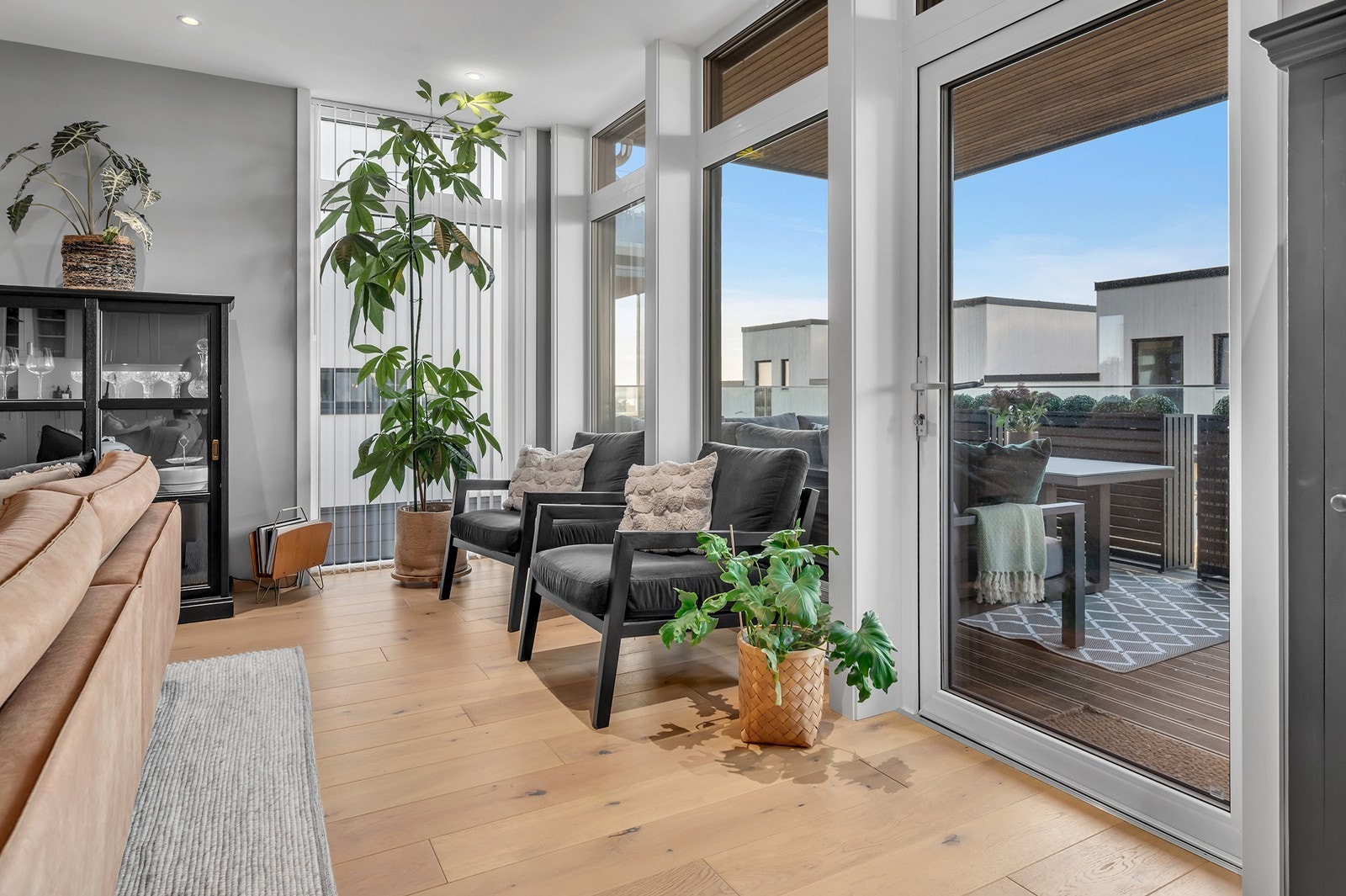 Flere store vindusflater i stuen og glassdør som leder ut til balkongen. Galleribilde