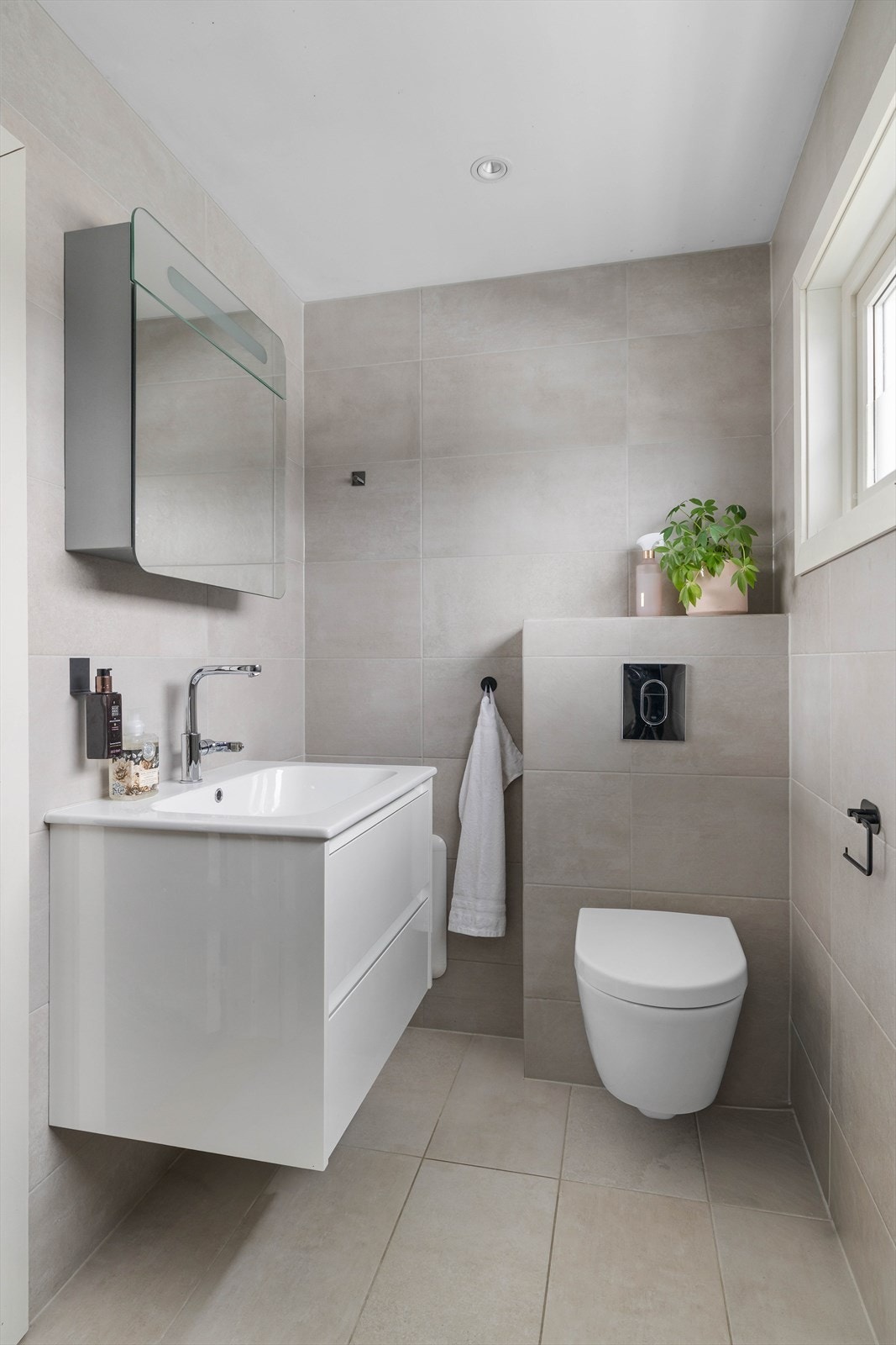 Badet er innredet med dusjvegger/hjørne med slukrenne ved veggen, veggmontert toalett og innredning med nedfelt servant Galleribilde