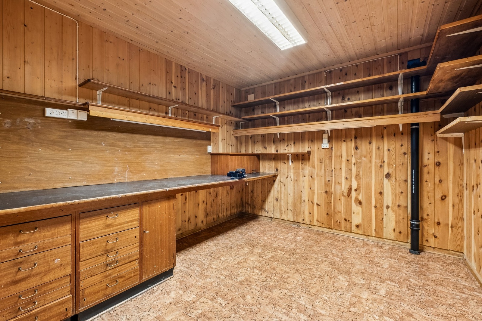 I kjeller er det også et romslig verksted med godt med oppbevaringsplass og praktisk arbeidsbenk. Vegger og tak i trepanel. Galleribilde