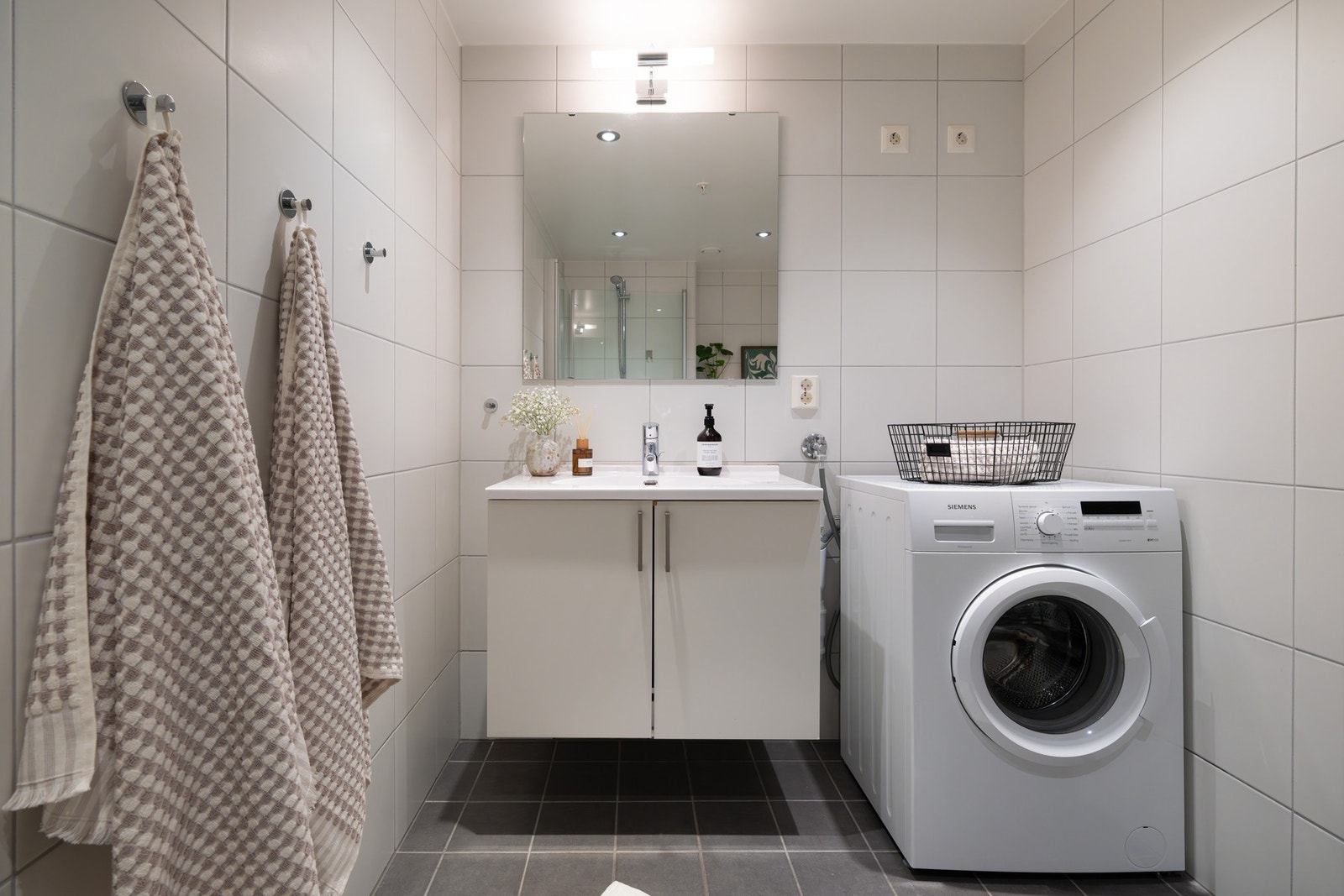 Badet er utstyrt med innredning med skap og nedfelt servant, speil med belysning over, veggmontert toalett, dusjvegger/hjørne og opplegg for vaskemaskin. Galleribilde