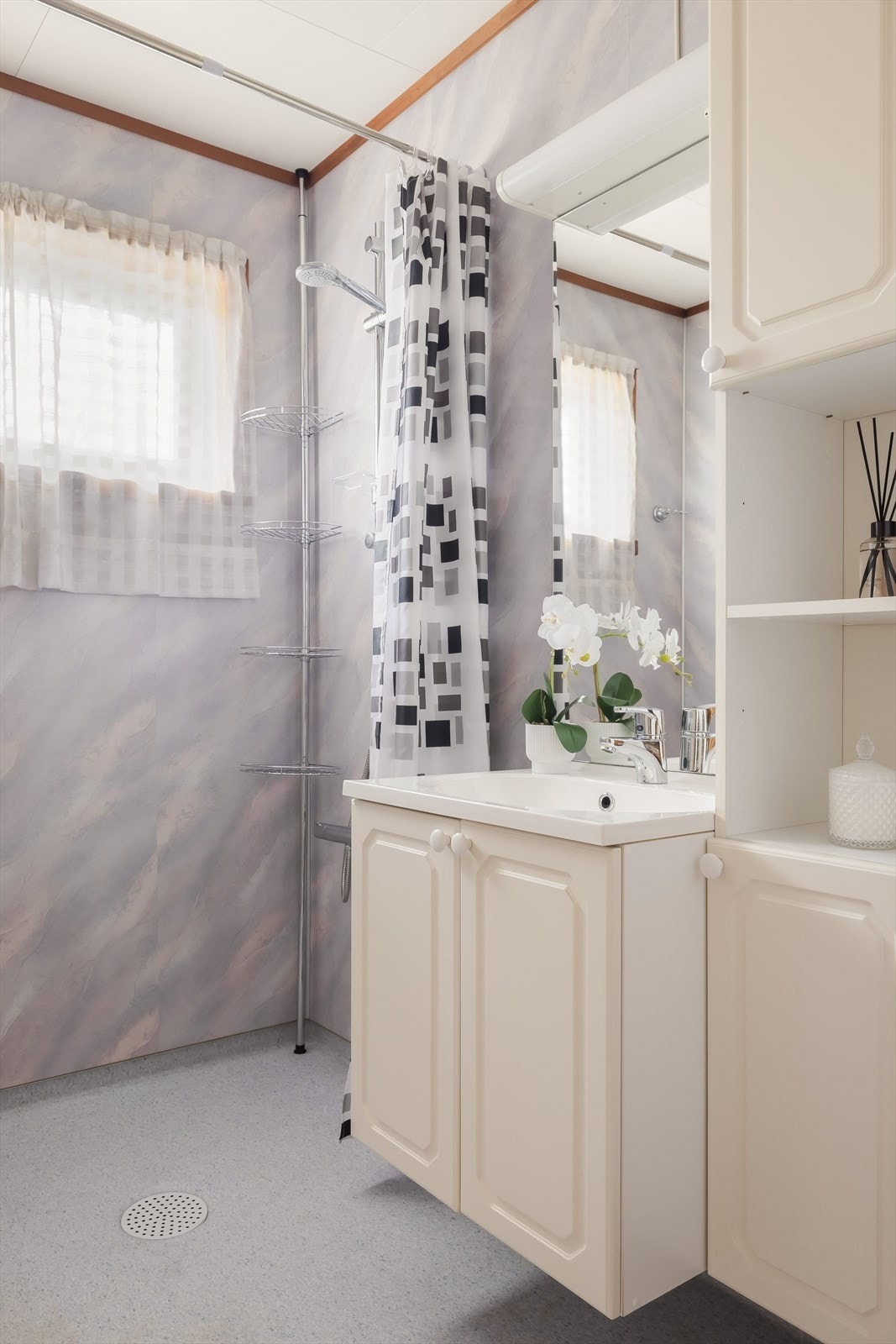 Badet har veggmontert dusjbatteri og dusjstang med forheng. Galleribilde