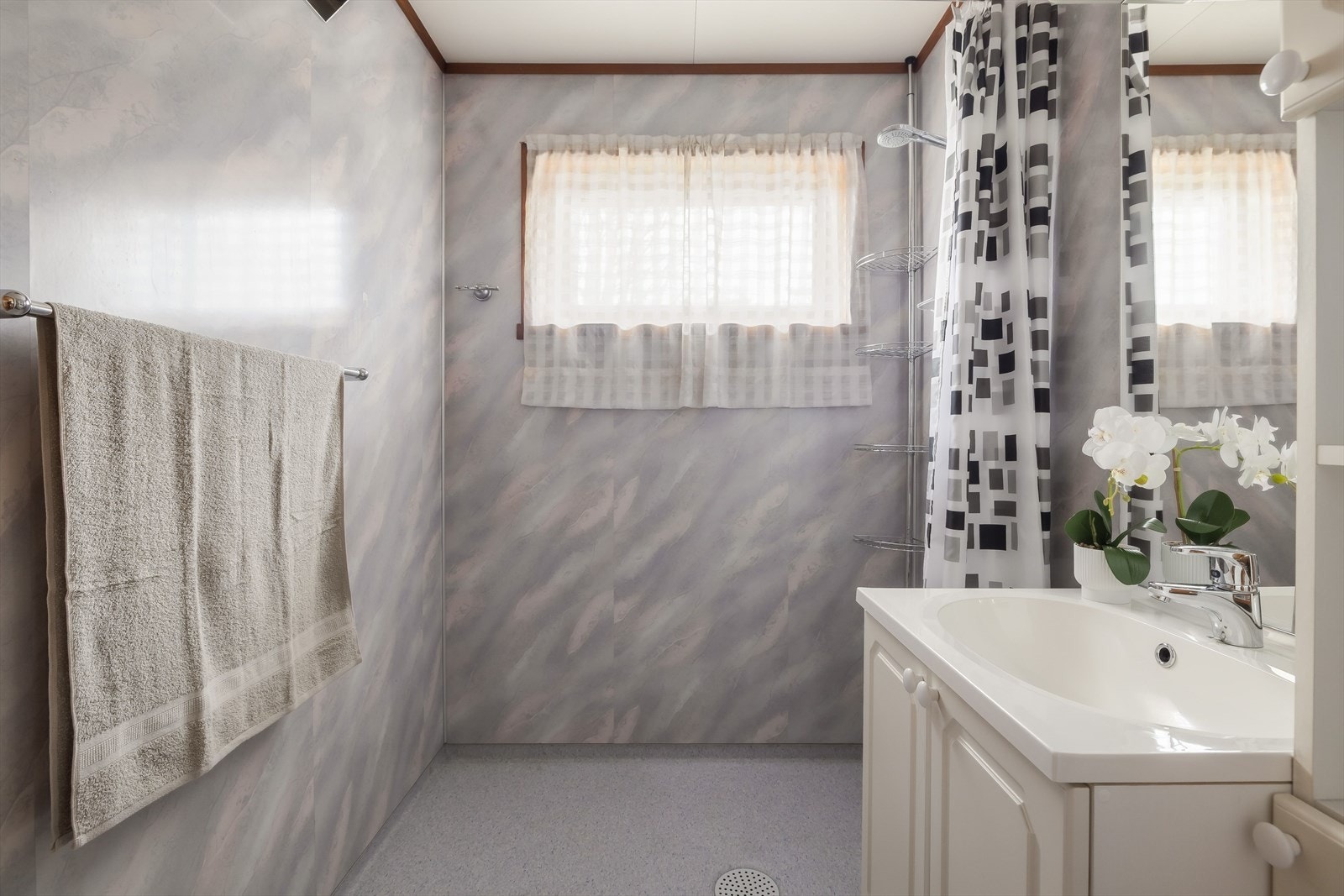 Bad med vegg og gulvflater fra ca. 2001. Veggene har våtromsplater og på gulvet er det belegg. Det er montert stråleovn. Galleribilde