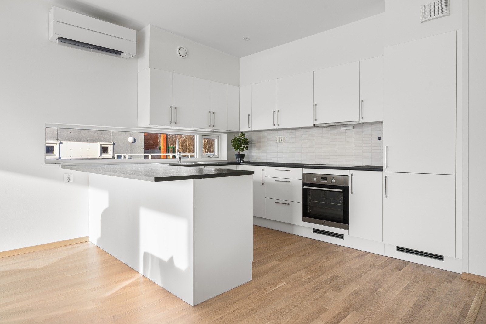 Kjøkken med glatte fronter og fliser over kjøkkenbenk. Her får du kvaliteter som integrert kjøl/frys, oppvaskmaskin, stekeovn og platetopp.