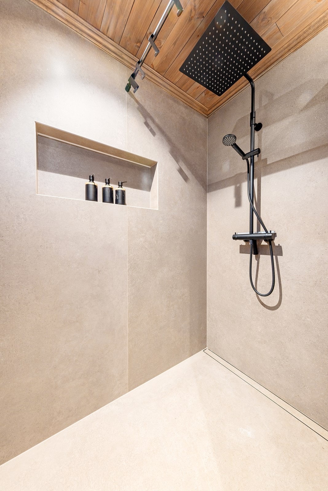 I dusjen er det en praktisk nisje for oppbevaring av såpe og tilbehør. Badet har moderne uttrykk med svarte detaljer. Galleribilde