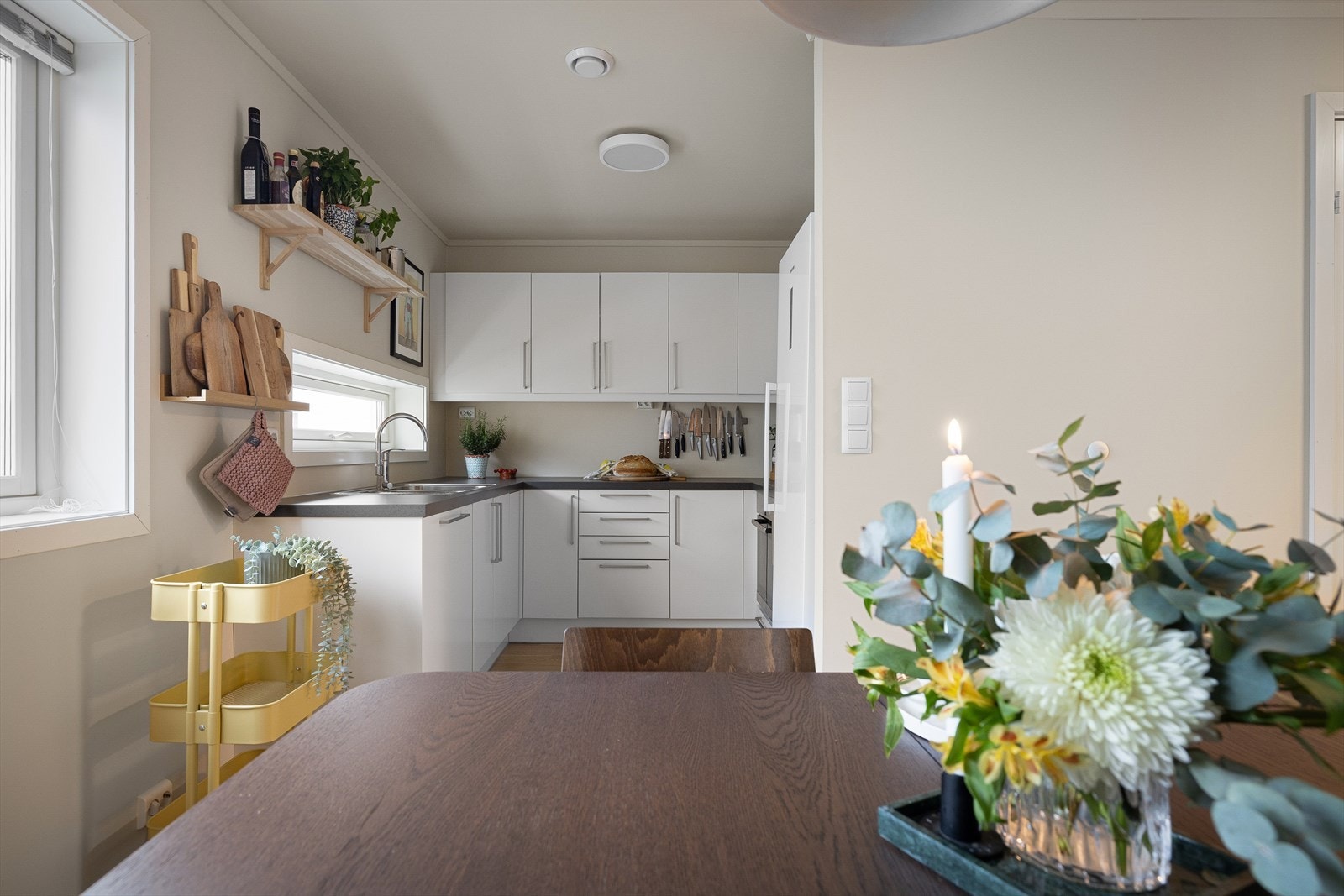 Kjøkkenet er praktisk plassert med gode arbeidsflater. Et moderne kjøkken med hvite, slette fronter. Galleribilde