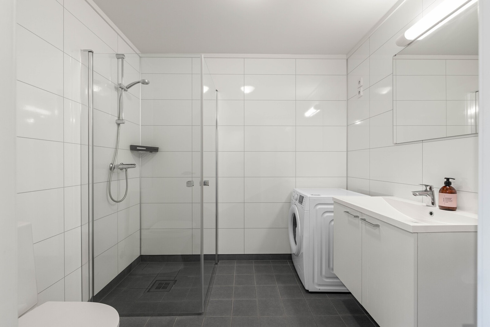 Romslig bad med dusj, toalett, vaskemaskin og stor servant. Galleribilde